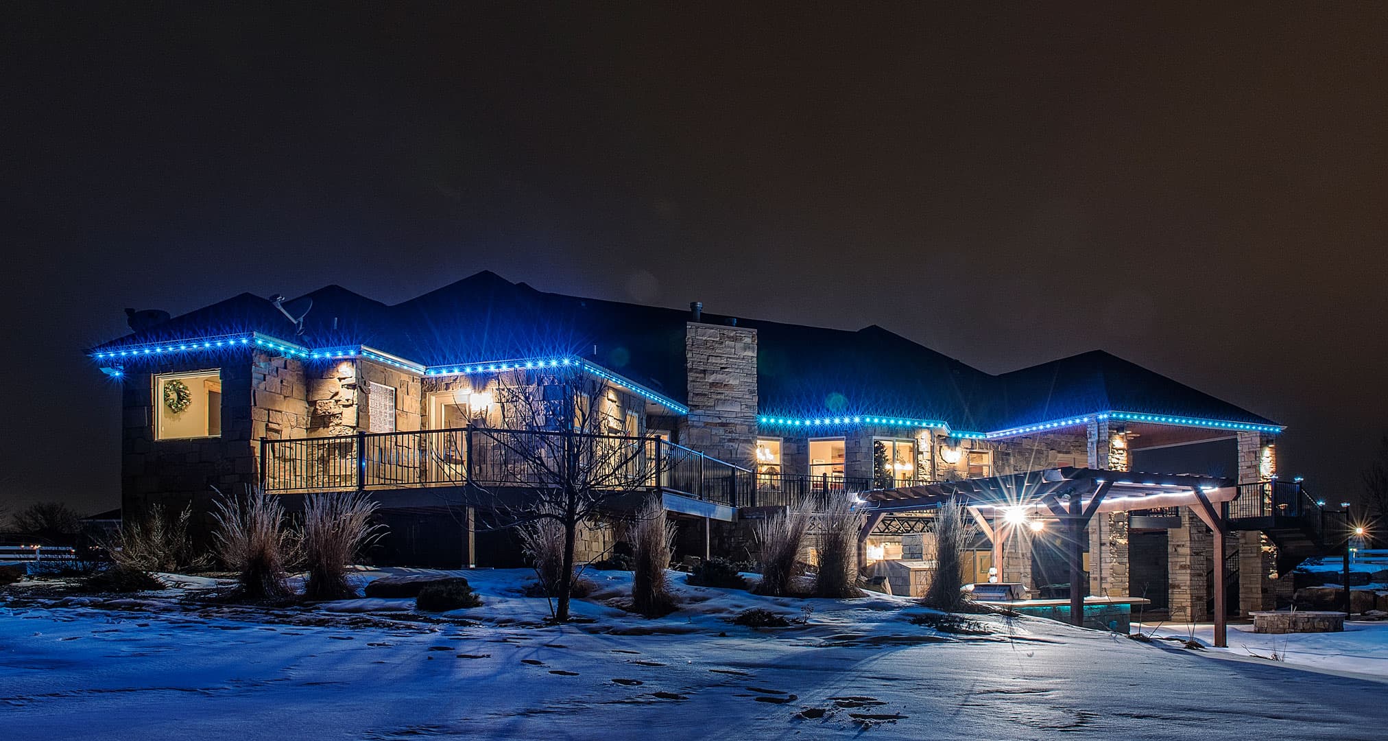Stone ranch home with permanent color-changing roofline lighting